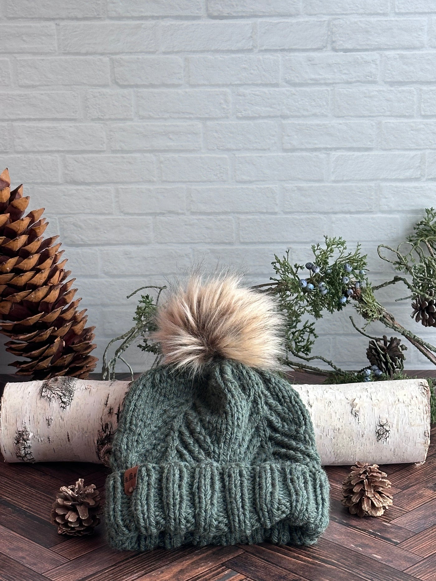 Norfolk green knit folded brim hat with evergreen design and brown faux fur Pom Pom