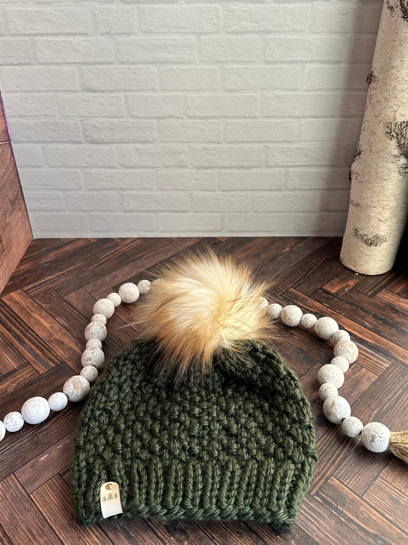 chunky knit evergreen hat with blond faux fur pom