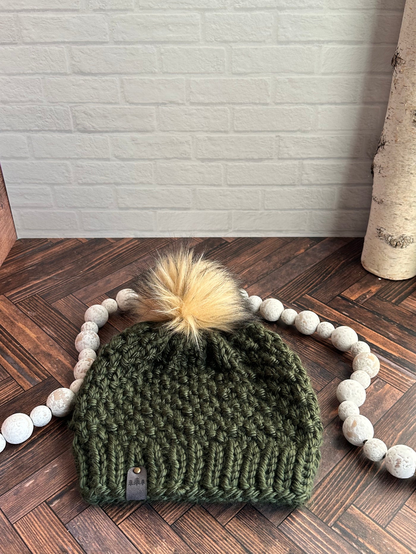 forest green chunky knit hat with light brown faux fur pom