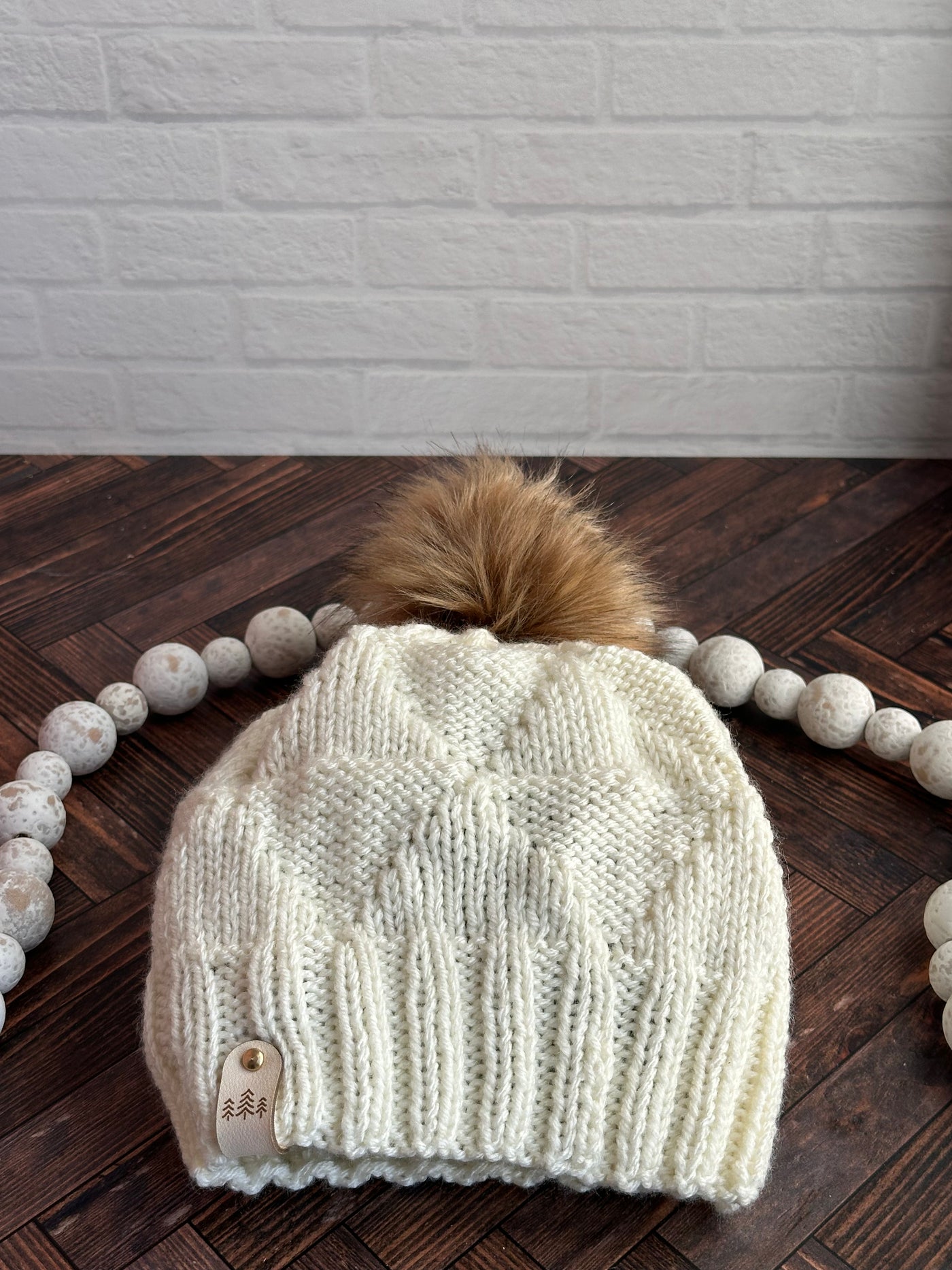 cream triangle knit hat with brown faux fur pom