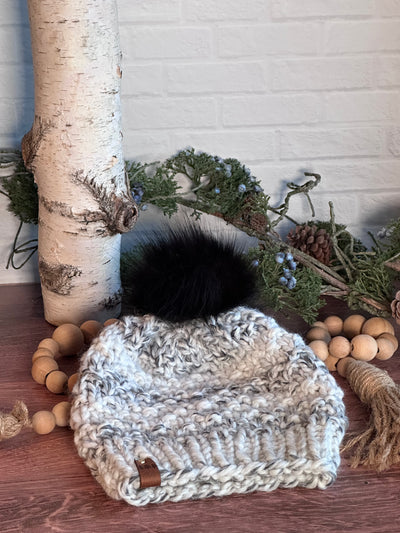 chunky handmade knit hat in yarn with grey and white.  Black faux fur removable Pom Pom