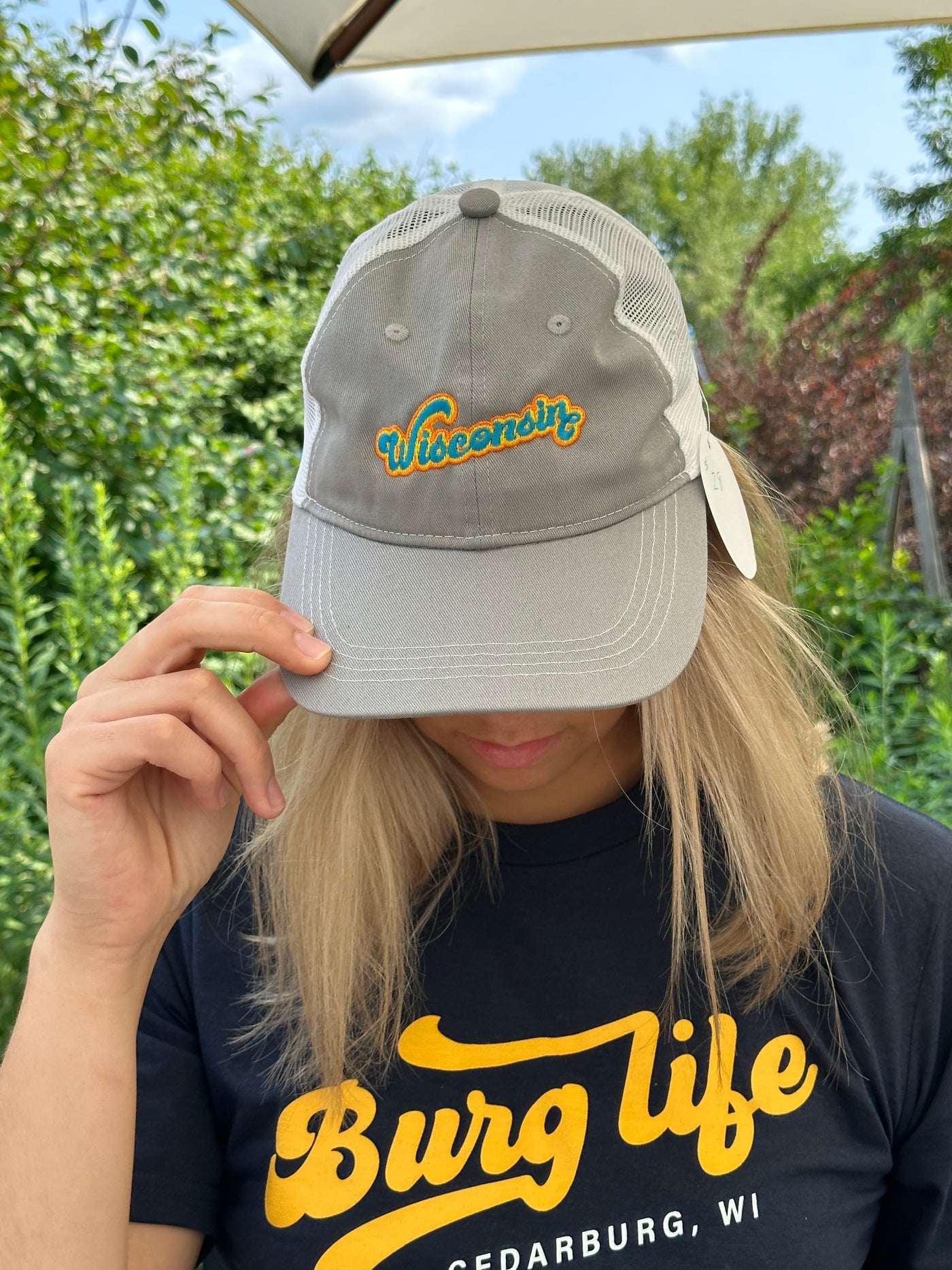 Retro inspired Wisconsin bubble font design in teal, orange and yellow on a grey and white mesh trucker style cap